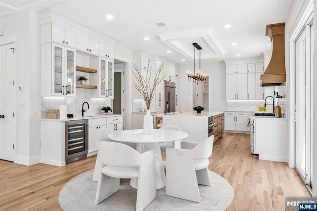 dining area with wet bar, beverage cooler, a notable chandelier, recessed lighting, and light wood-style flooring