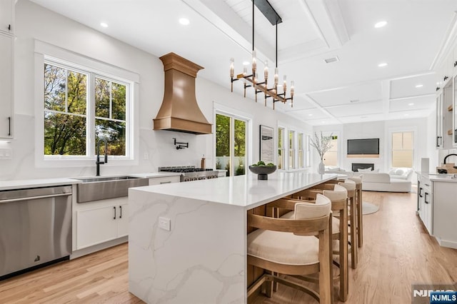 kitchen with dishwasher, a sink, custom exhaust hood, open floor plan, and light wood-style flooring