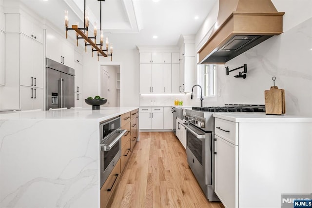 kitchen featuring high quality appliances, white cabinetry, custom exhaust hood, recessed lighting, and light wood-style flooring