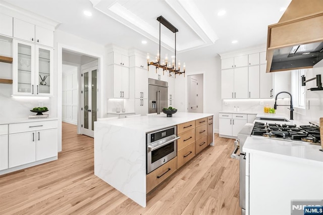 kitchen featuring light wood-type flooring, a sink, a center island, and high quality appliances