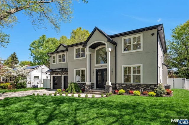 view of front of house featuring stucco siding, driveway, a front yard, and fence