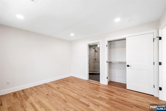 unfurnished bedroom with baseboards, connected bathroom, and light wood-style flooring