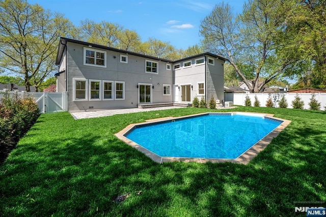 rear view of house featuring a fenced backyard, stucco siding, a gate, a patio area, and a lawn