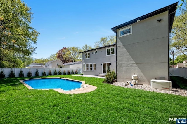 rear view of property with a lawn, a fenced in pool, a fenced backyard, and stucco siding
