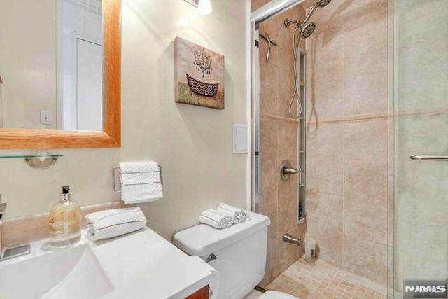 bathroom with toilet, a shower stall, and vanity