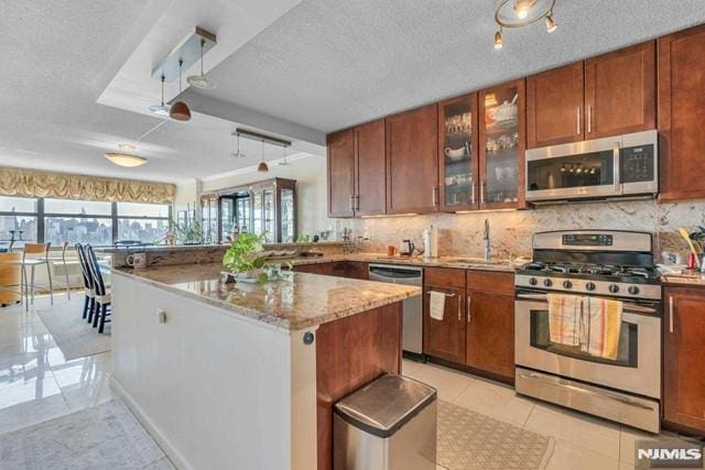 kitchen featuring backsplash, stainless steel appliances, a sink, and light tile patterned floors