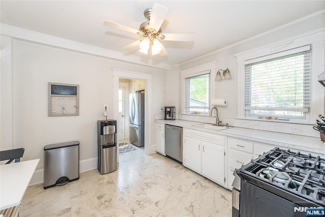 kitchen with marble finish floor, light countertops, white cabinetry, a sink, and appliances with stainless steel finishes