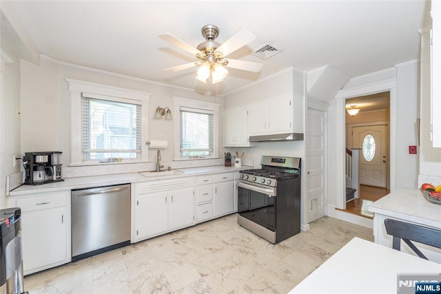 kitchen featuring appliances with stainless steel finishes, a sink, light countertops, under cabinet range hood, and white cabinetry