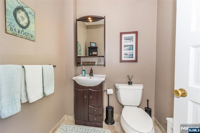 bathroom featuring baseboards, toilet, and vanity