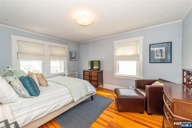 bedroom with light wood-style floors, ornamental molding, and baseboards