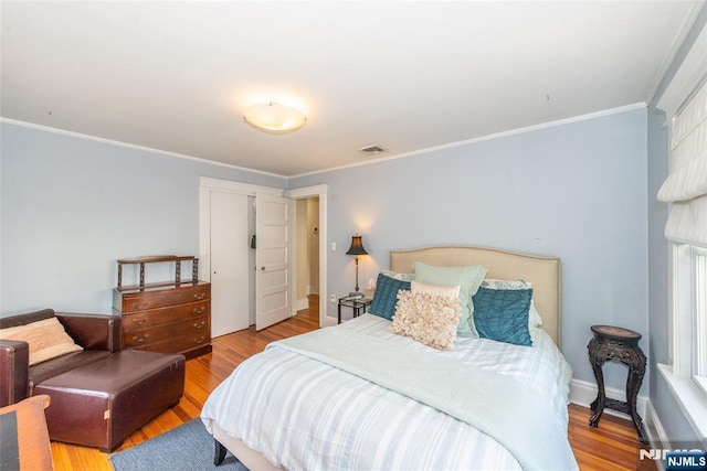 bedroom featuring ornamental molding, wood finished floors, and visible vents
