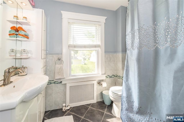 bathroom featuring radiator heating unit, tile walls, tile patterned flooring, and vanity