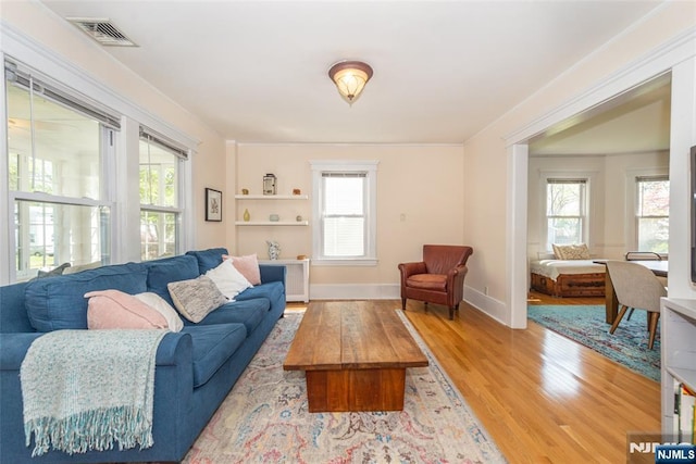 living room with baseboards, a wealth of natural light, wood finished floors, and visible vents