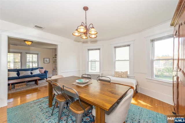 dining room with an inviting chandelier, a wealth of natural light, and light wood-style flooring