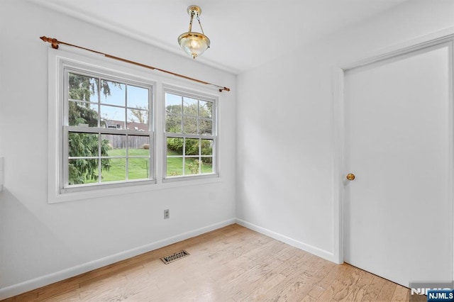 unfurnished room with baseboards, visible vents, and wood finished floors