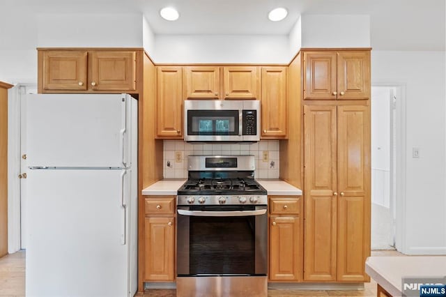kitchen featuring light countertops, recessed lighting, appliances with stainless steel finishes, and decorative backsplash