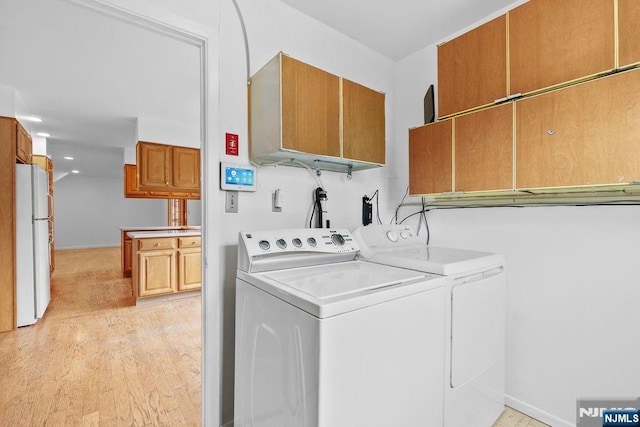 laundry room featuring baseboards, cabinet space, washer and dryer, and light wood-type flooring