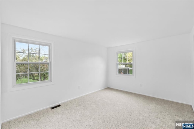 spare room with carpet floors, baseboards, and visible vents