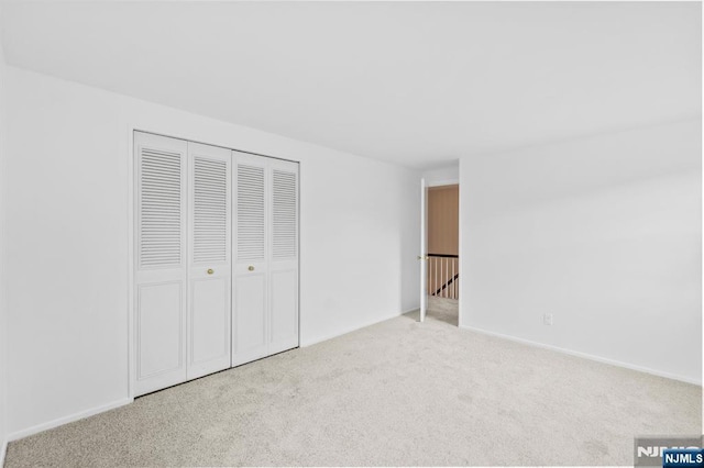 unfurnished bedroom with a closet, baseboards, and carpet flooring