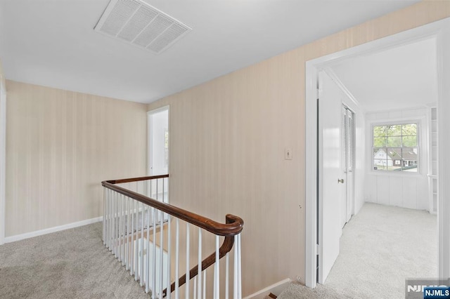 corridor with visible vents, carpet, and an upstairs landing