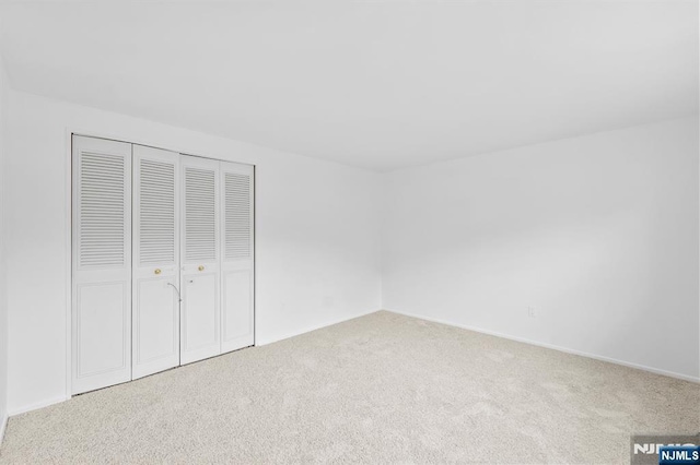 unfurnished bedroom featuring carpet floors, baseboards, and a closet