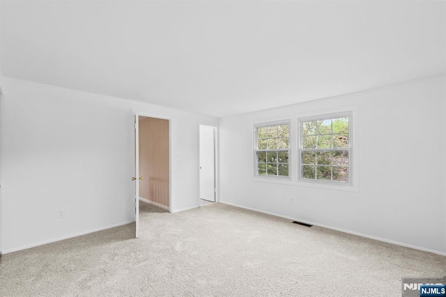 empty room featuring visible vents, baseboards, and light carpet