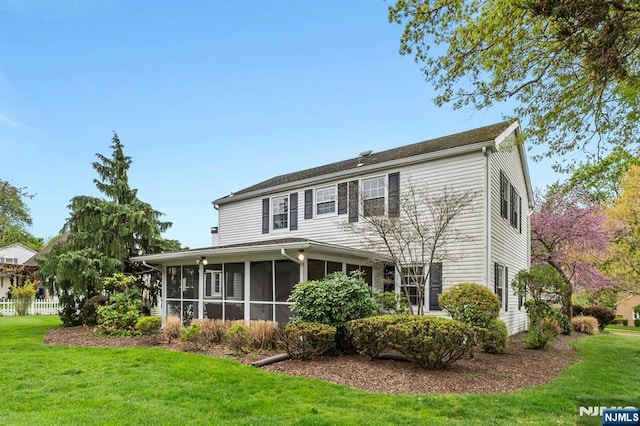 rear view of house with a lawn and a sunroom
