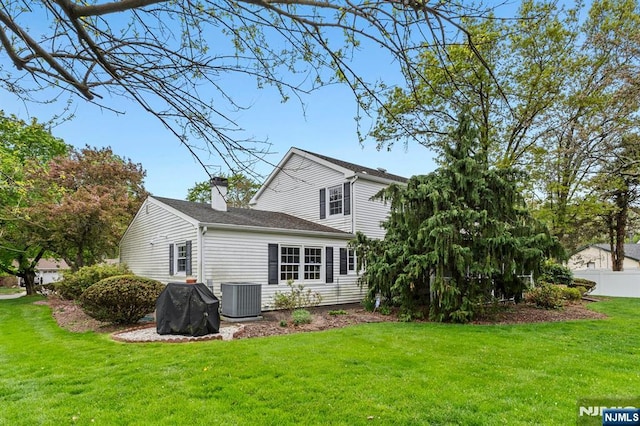 back of house with a lawn, central AC, fence, and a chimney