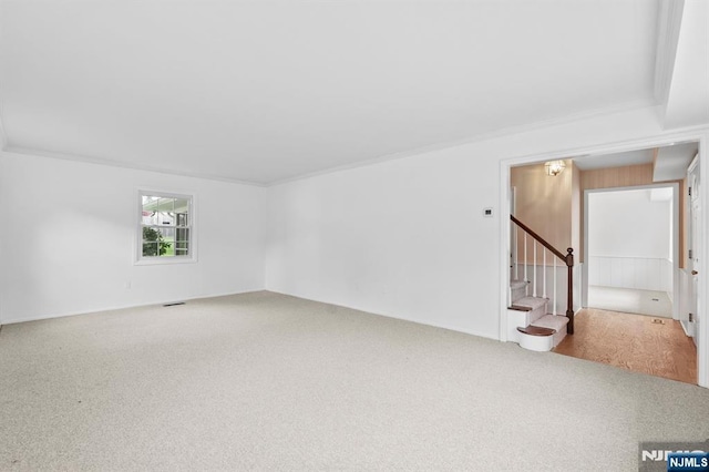carpeted empty room with visible vents, ornamental molding, and stairway