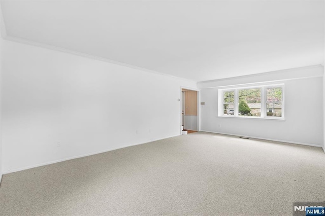 carpeted spare room featuring baseboards, ornamental molding, and visible vents