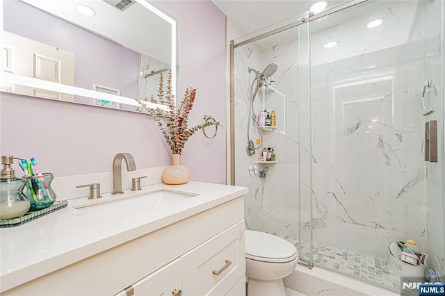 bathroom featuring toilet, a marble finish shower, marble finish floor, and vanity