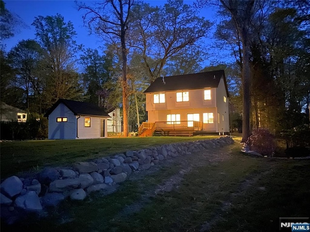 rear view of house featuring a lawn, a deck, and an outbuilding