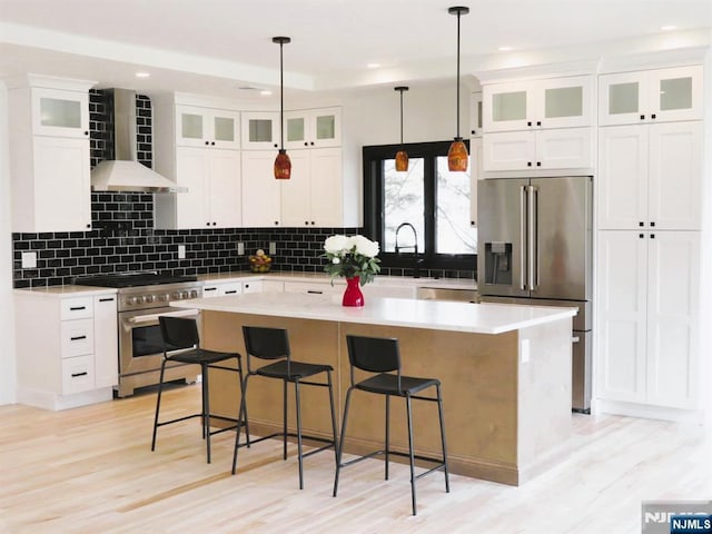 kitchen with decorative backsplash, wall chimney exhaust hood, a kitchen island, and high quality appliances