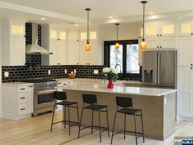 kitchen with wall chimney range hood, a center island, decorative backsplash, and premium appliances