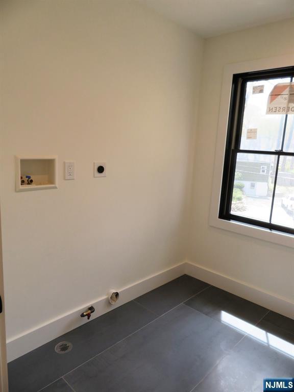 washroom featuring laundry area, hookup for a washing machine, hookup for a gas dryer, baseboards, and dark tile patterned floors