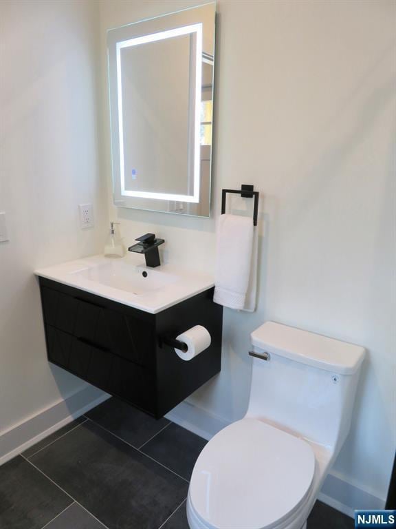 bathroom featuring baseboards, tile patterned floors, vanity, and toilet