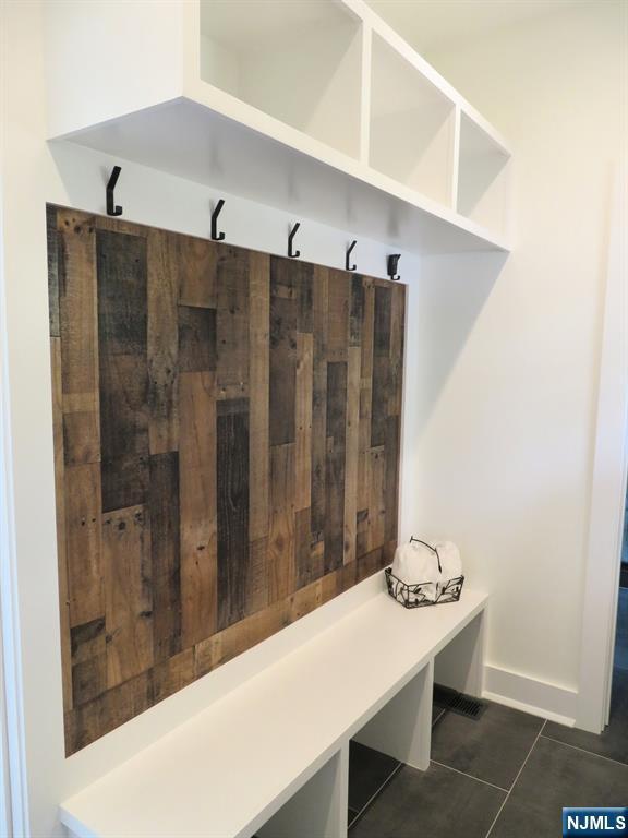 mudroom with dark tile patterned flooring and baseboards