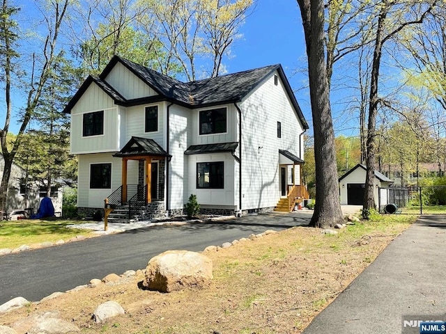 view of front facade featuring an outdoor structure, board and batten siding, metal roof, and a standing seam roof