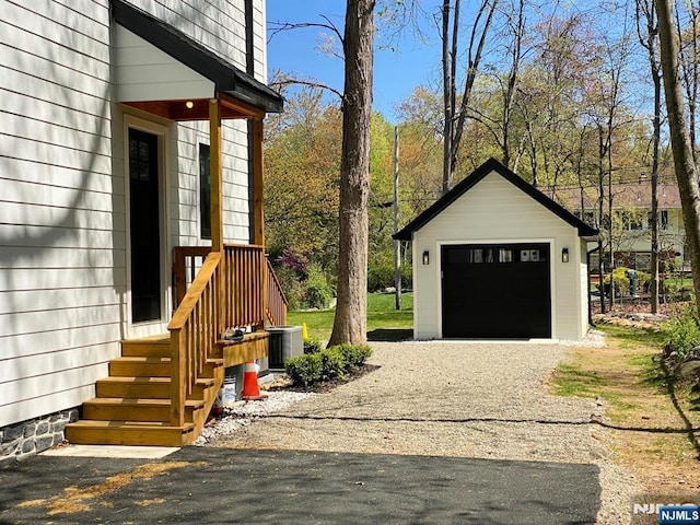 detached garage featuring driveway and cooling unit