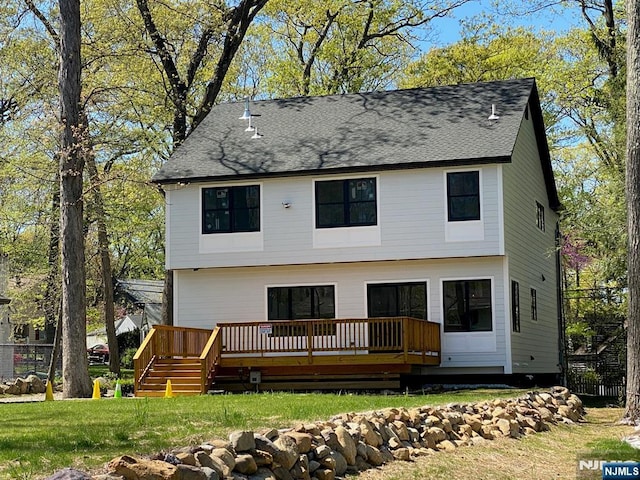 view of front of home featuring roof with shingles, fence, a wooden deck, and a front yard