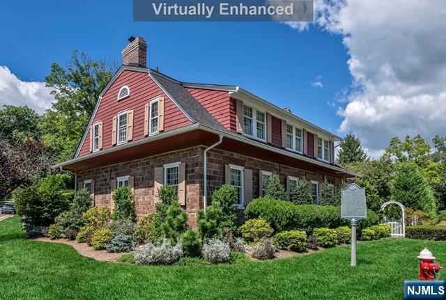2 Wierimus Ln, Hillsdale, NJ 07642 - view of side of home featuring a yard, a chimney, stone siding, and a gambrel roof
