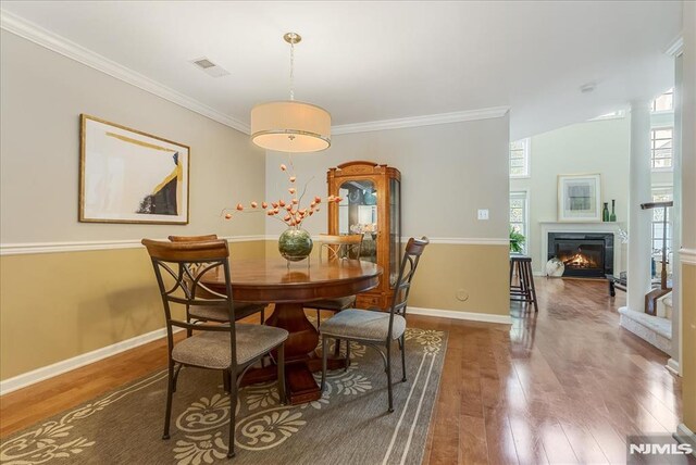 dining area featuring crown molding, baseboards, visible vents, and wood finished floors