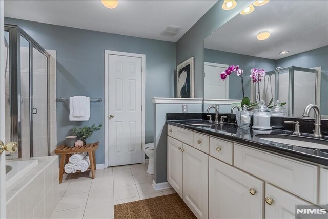 full bath with double vanity, a shower stall, a sink, and tile patterned flooring