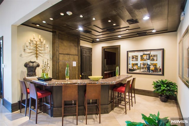 bar with baseboards, light tile patterned flooring, wet bar, and visible vents