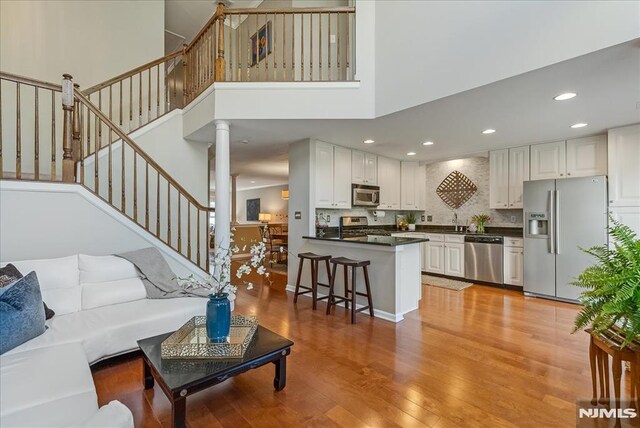 living room featuring recessed lighting, a high ceiling, stairway, and light wood finished floors