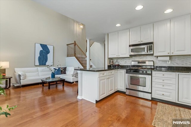 kitchen featuring white cabinetry, a peninsula, backsplash, and stainless steel appliances