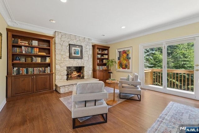 living room featuring crown molding, a fireplace, wood finished floors, baseboards, and recessed lighting