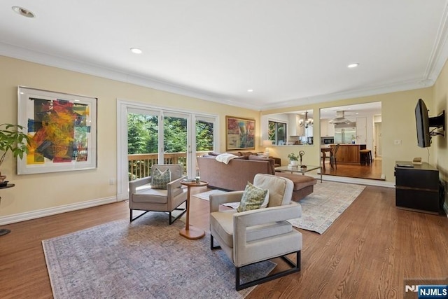 living area featuring baseboards, ornamental molding, wood finished floors, and recessed lighting
