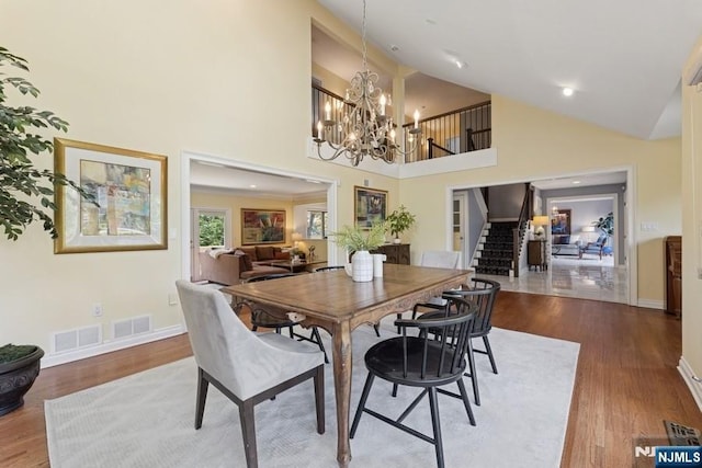 dining area featuring visible vents, wood finished floors, stairway, and an inviting chandelier