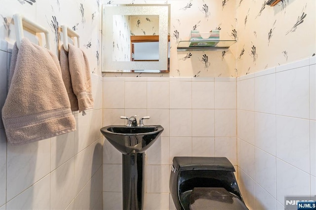 bathroom featuring wallpapered walls and tile walls
